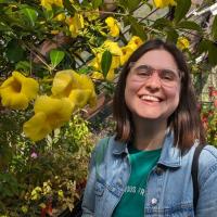 A picture of Nicola in front of some yellow flowers.